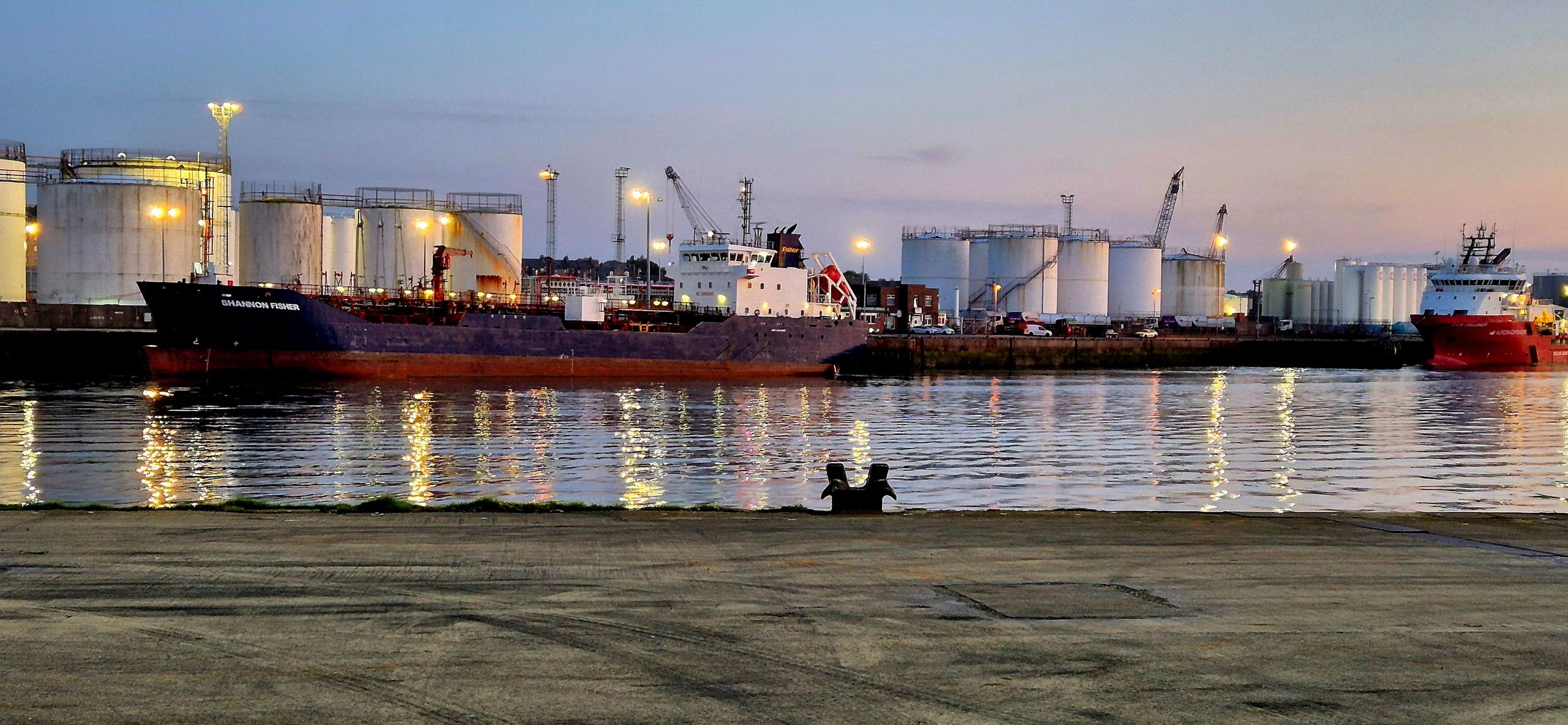 Commercial harbour at dusk with energy terminal infrastructure